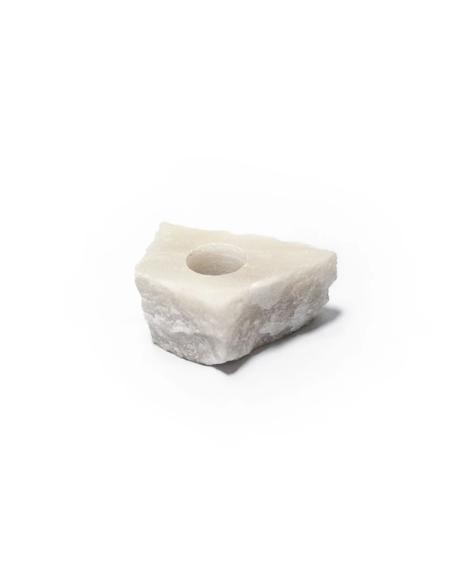 The 'Lithic Candle Holder' created by Jannis Schäfer Studio, made from a reclaimed marble tabletop. The design features a tall, tapered candle held by a square marble base. This upcycled, recycled, and transformed piece is part of a series of derivative designs.