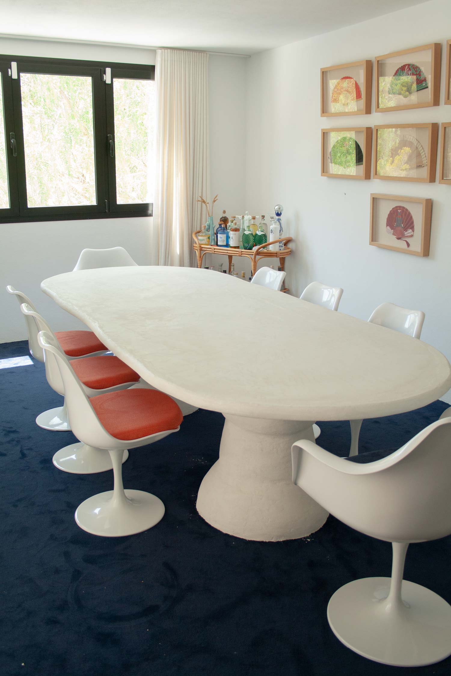 Custom made dining table, Ibiza, called “Artefact dining table“ with two artefact, totem like bases and a long oval playful imperfect shape tabletop. Materials are hempcrete, limestone, wood, mortex. design by studio jannis schaefer, tulip chair