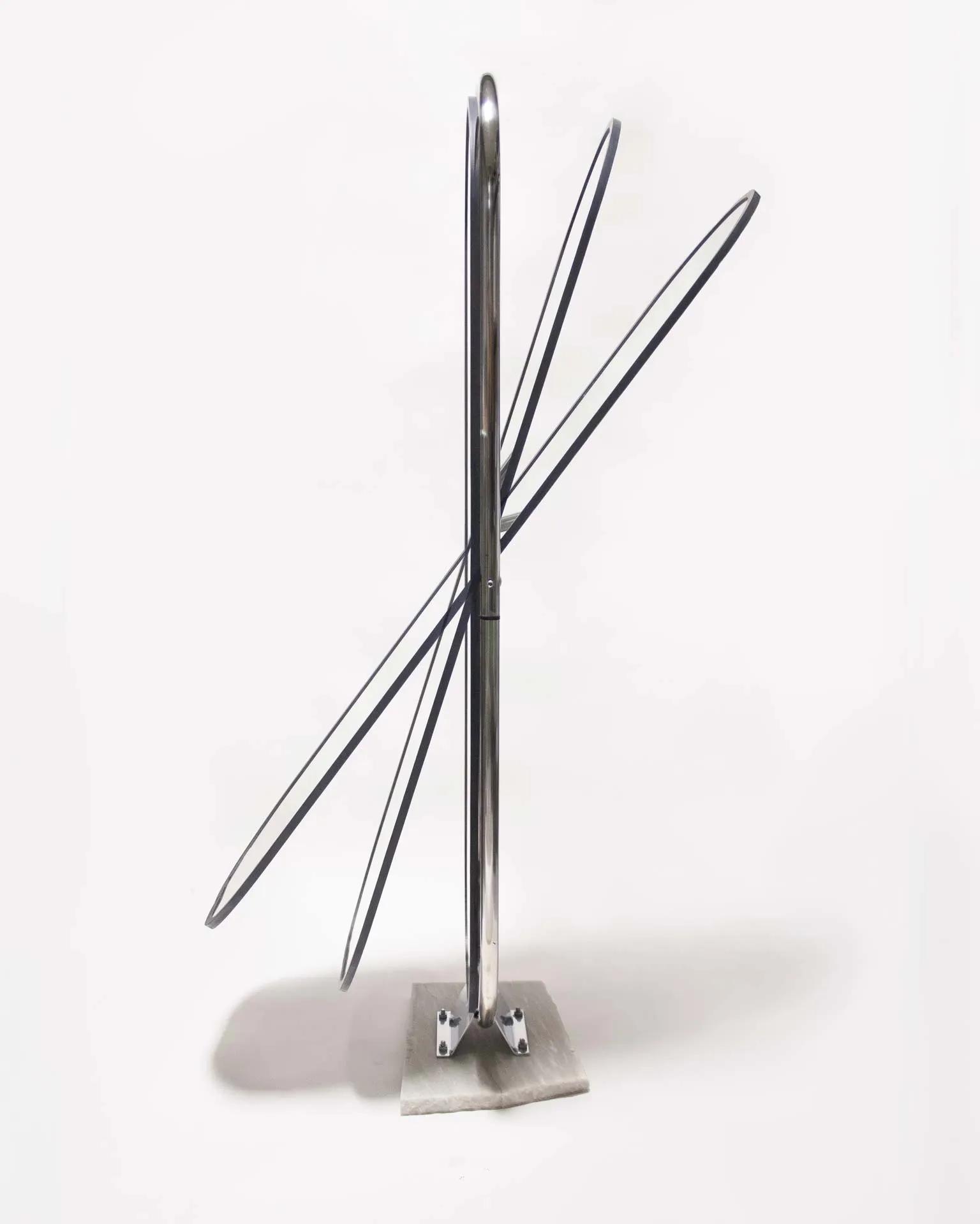 A mirror created by Jannis Schäfer Studio, made from upcycled theft detectors and a reclaimed marble tabletop. The design features a tall, narrow, swingable mirror framed in a chrome structure with a marble base. This object, titled 'Stealing Beauty,' is part of a series of recycled and transformed designs.