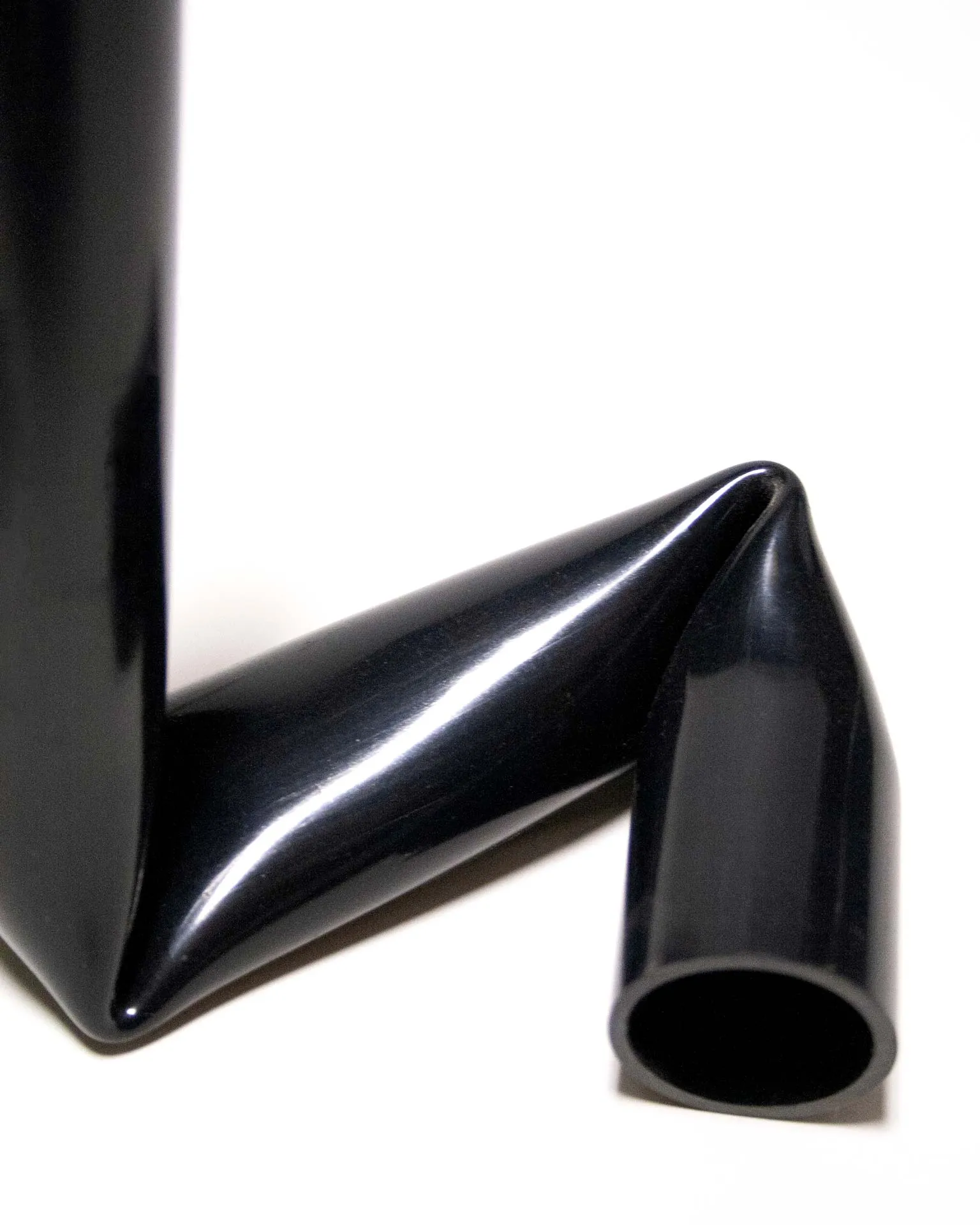 "A sleek black candle holder made from an upcycled PVC tube, creatively bent into an L-shape. Designed by Jannis Schäfer Studio, the piece demonstrates innovative use of reclaimed materials and is part of the 'Derivatives' series, emphasizing sustainable design practices.”