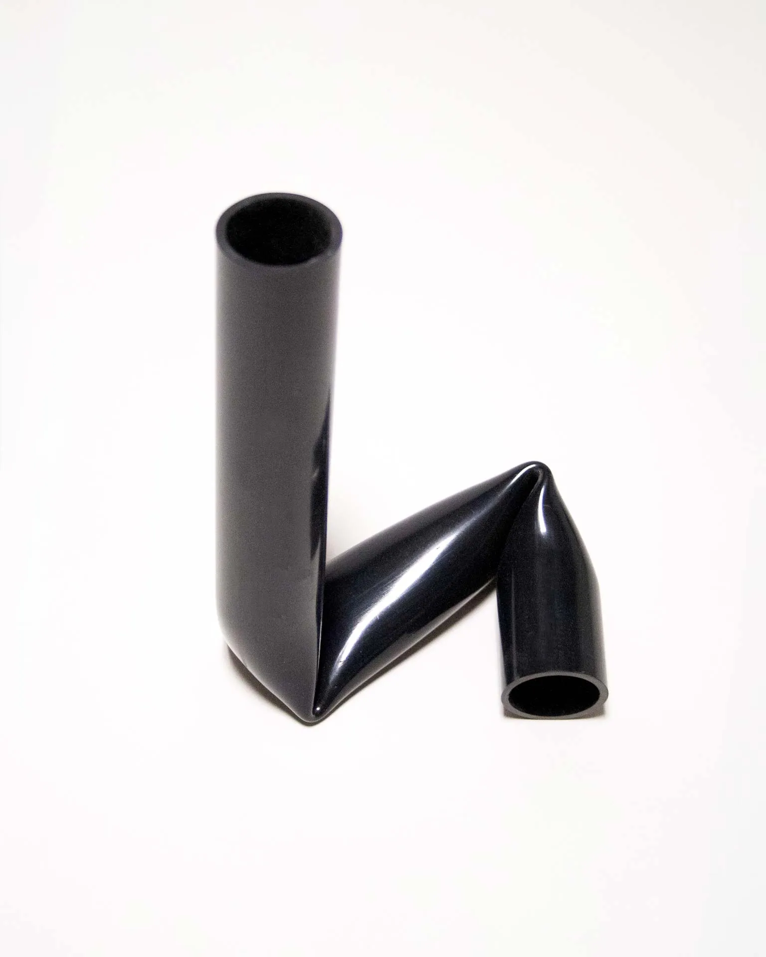 "A sleek black candle holder made from an upcycled PVC tube, creatively bent into an L-shape. Designed by Jannis Schäfer Studio, the piece demonstrates innovative use of reclaimed materials and is part of the 'Derivatives' series, emphasizing sustainable design practices.”