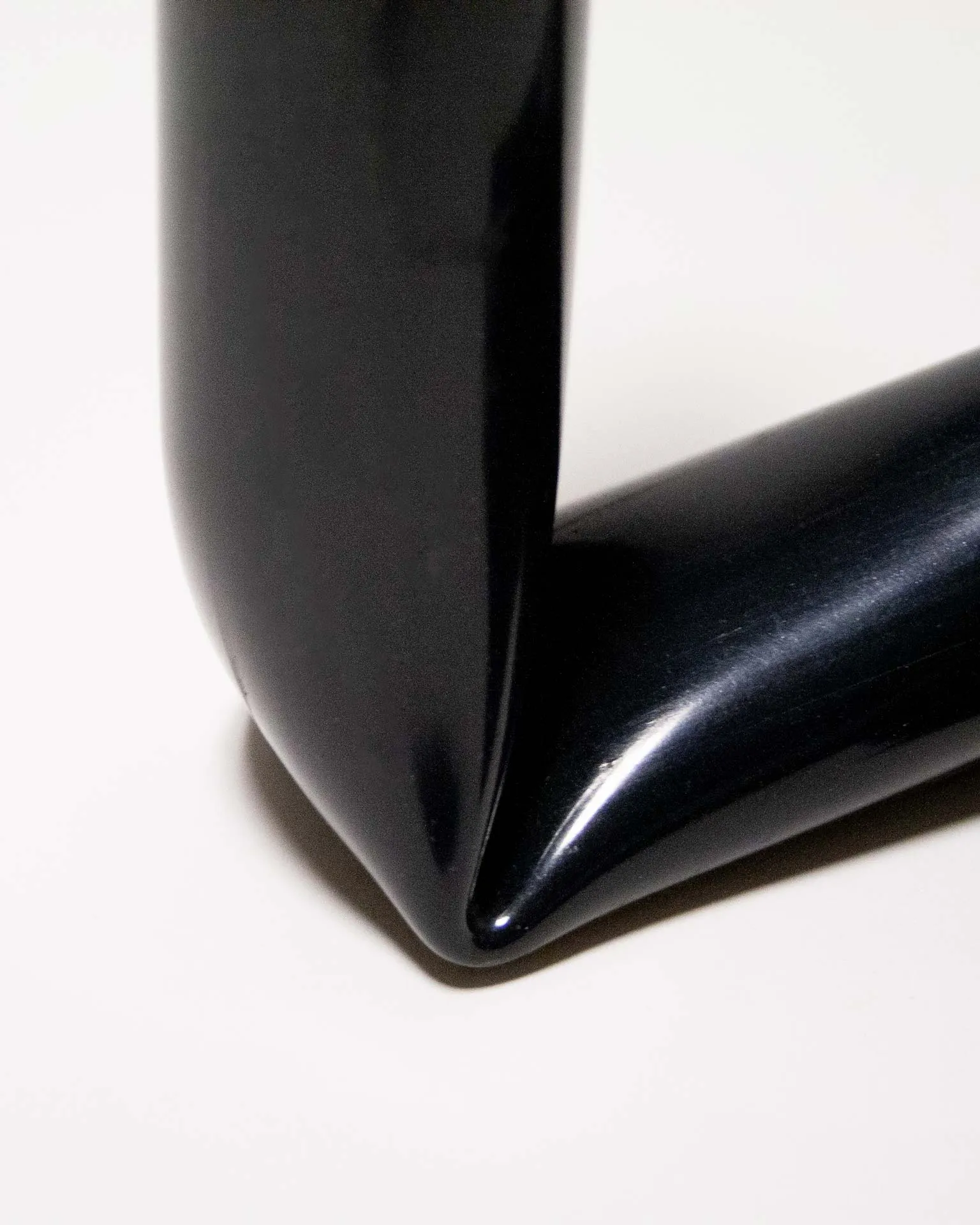 "A sleek black candle holder made from an upcycled PVC tube, creatively bent into an L-shape. Designed by Jannis Schäfer Studio, the piece demonstrates innovative use of reclaimed materials and is part of the 'Derivatives' series, emphasizing sustainable design practices.”