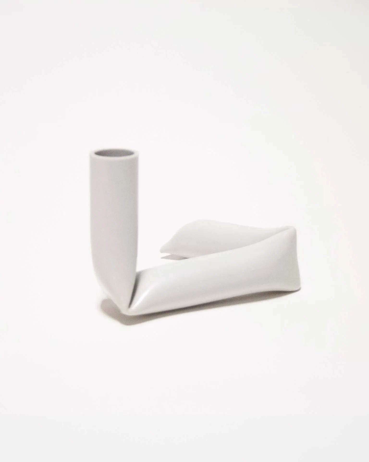 "A sleek black candle holder made from an upcycled PVC tube, creatively bent into an L-shape. Designed by Jannis Schäfer Studio, the piece demonstrates innovative use of reclaimed materials and is part of the 'Derivatives' series, emphasizing sustainable design practices.”