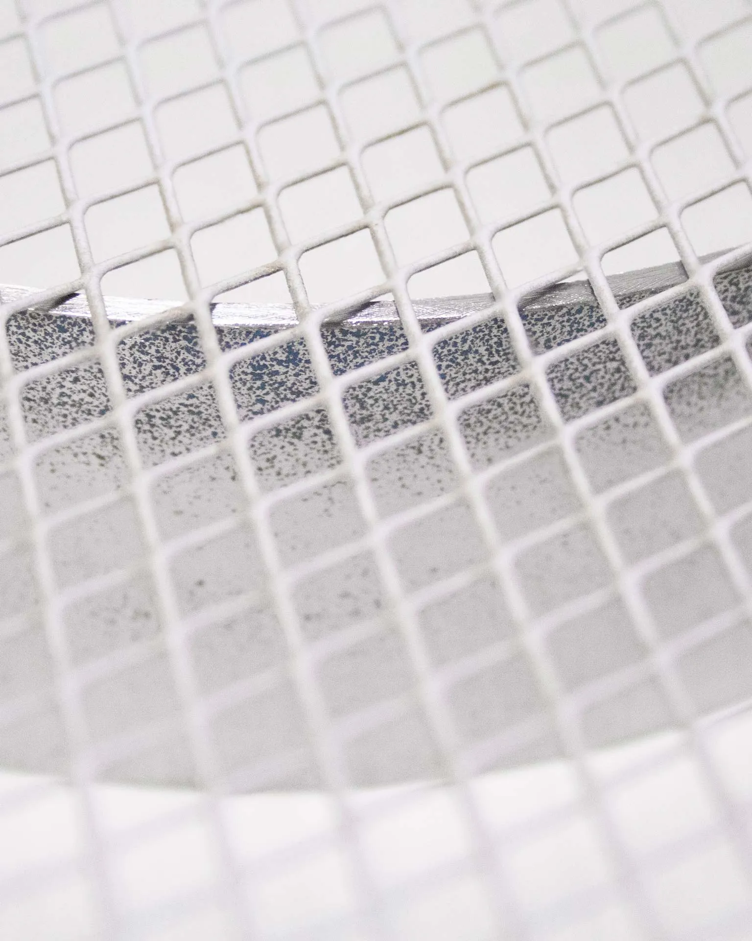 "A minimalist fruit bowl designed by Jannis Schäfer Studio, crafted from an upcycled ventilator shield. The bowl features a circular mesh design, highlighting the studio's commitment to transforming reclaimed materials. This piece is part of the 'Derivatives' series, focusing on innovative and sustainable design.”