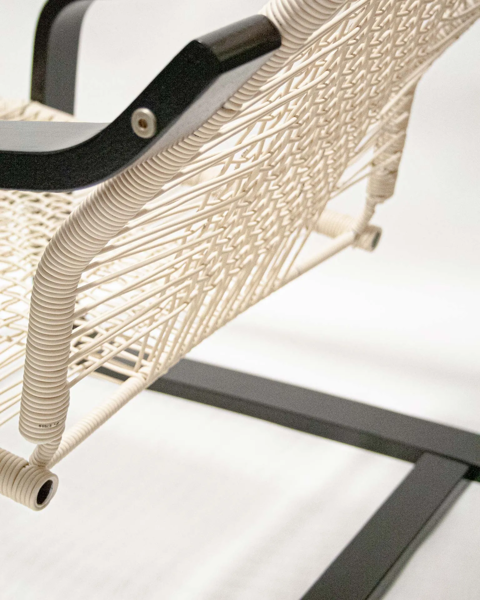 The 'Telefonica Lounge Chair' created by Jannis Schäfer Studio, made from reclaimed telephone cables woven into a supportive seat and backrest. The chair features a sleek black frame with curved armrests and legs. This upcycled, recycled, and transformed piece is part of a series of derivative designs.