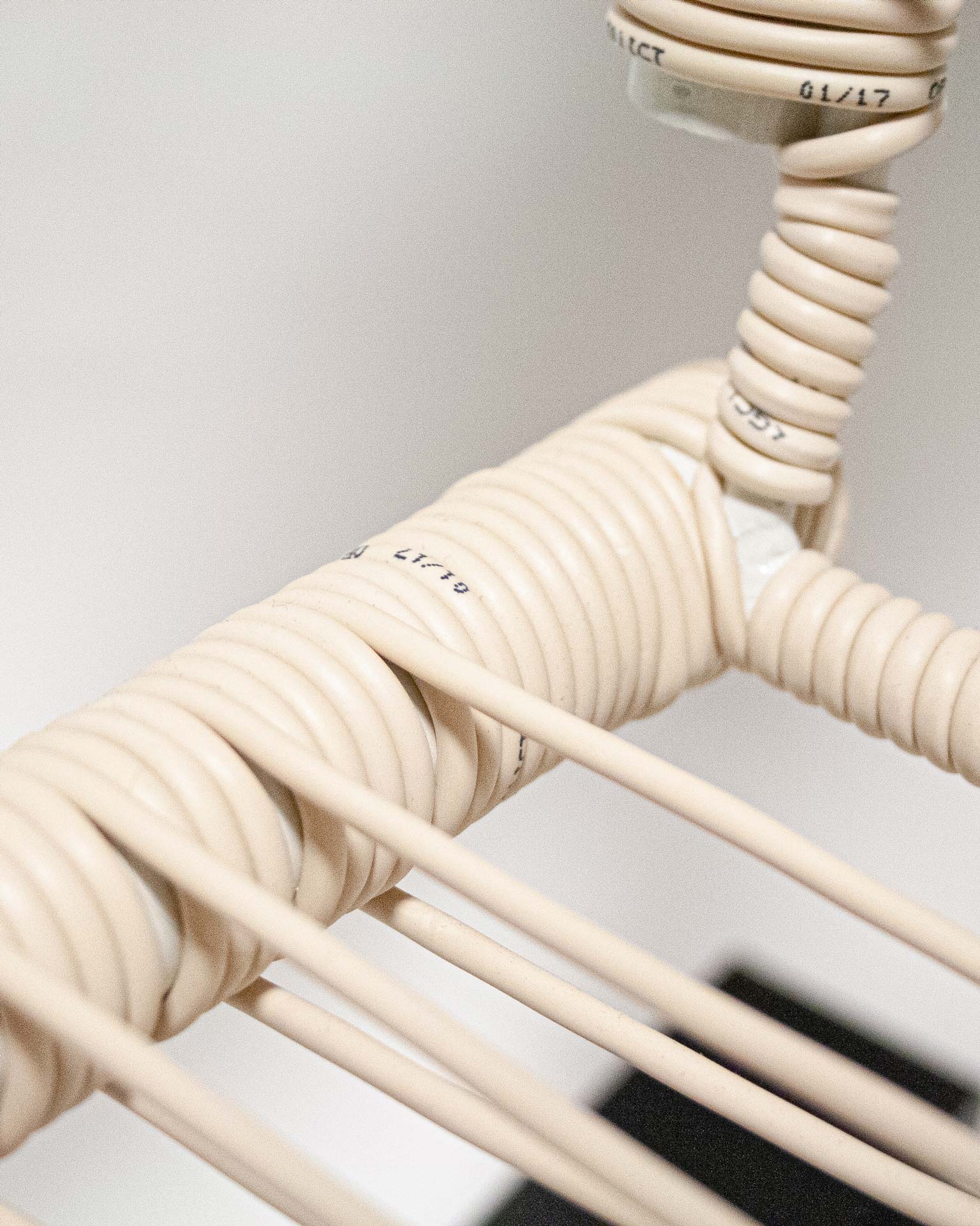 The 'Telefonica Lounge Chair' created by Jannis Schäfer Studio, made from reclaimed telephone cables woven into a supportive seat and backrest. The chair features a sleek black frame with curved armrests and legs. This upcycled, recycled, and transformed piece is part of a series of derivative designs.