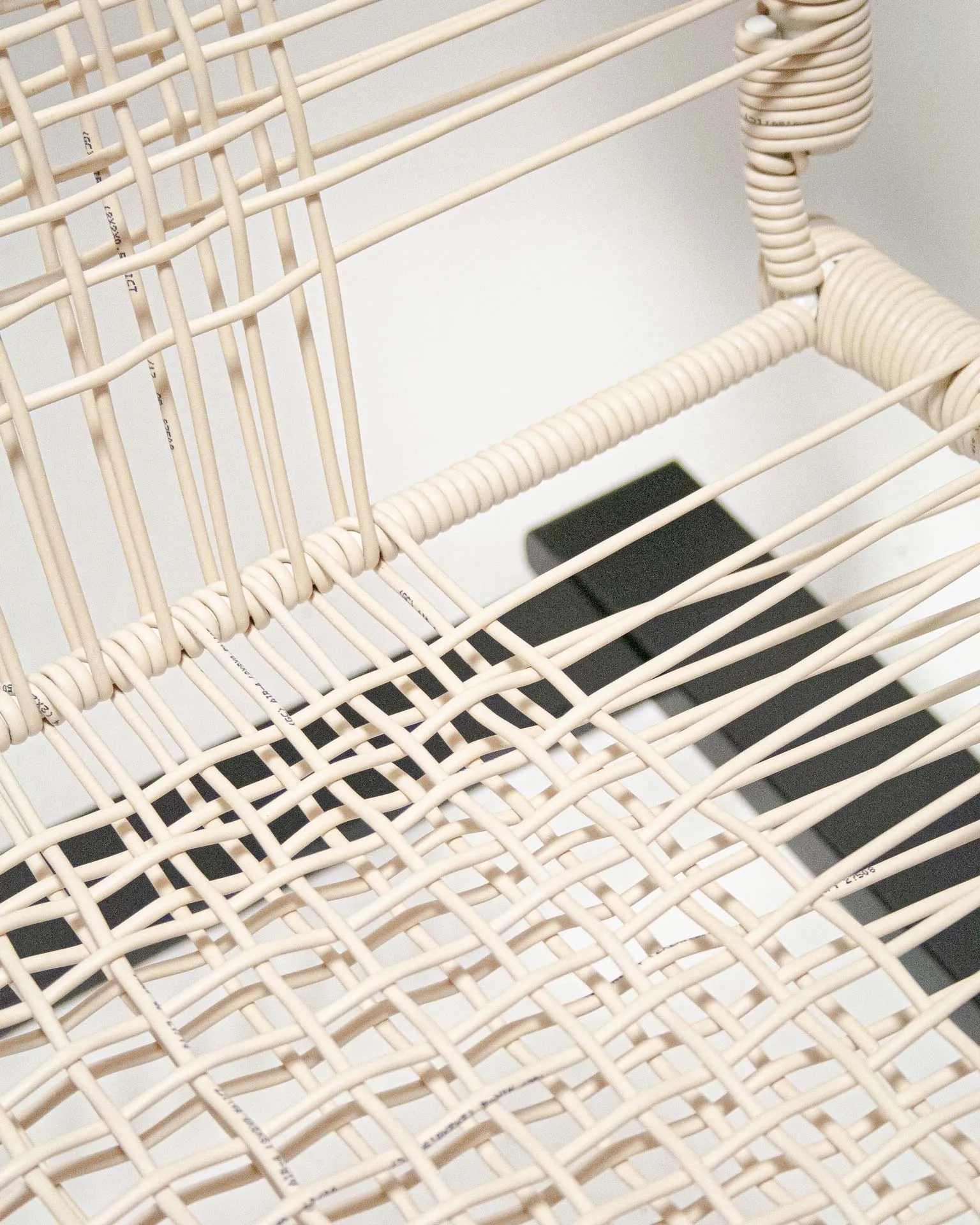 The 'Telefonica Lounge Chair' created by Jannis Schäfer Studio, made from reclaimed telephone cables woven into a supportive seat and backrest. The chair features a sleek black frame with curved armrests and legs. This upcycled, recycled, and transformed piece is part of a series of derivative designs.