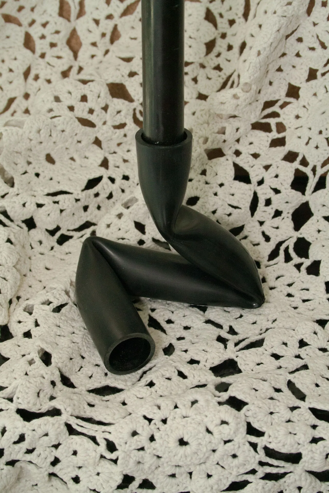 A candle holder created by Jannis Schäfer Studio, made from upcycled PVC tube. The design features a unique, twisted form with two cylindrical openings for candles. This transformed and reclaimed material piece is part of a series of derivative designs.