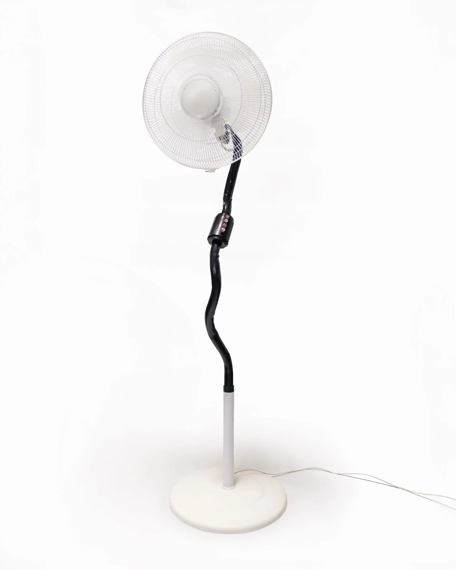The 'Bent Pipe Blower,' created by Jannis Schäfer Studio, is a ventilator sculpture made from a reclaimed PVC tube and Precious Plastic samples as knobs and buttons. The design features a standing fan with a curved black pipe as the stand, a white circular base, and a clear fan head. This upcycled, recycled, and transformed piece is part of a series of derivative designs.