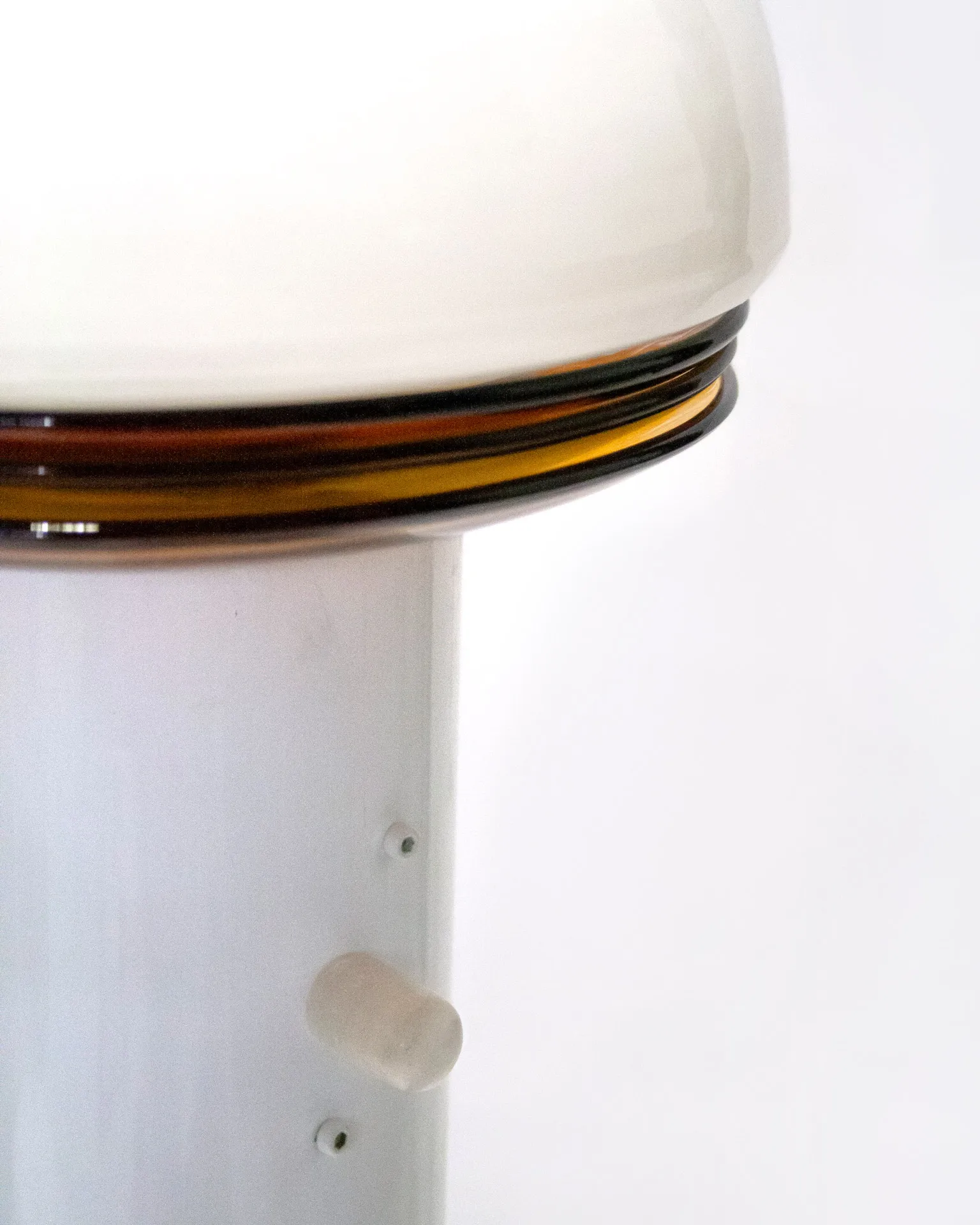 The 'Toadstool Lamp,' created by Jannis Schäfer Studio, is a dimmable lamp made from reclaimed tiles and a metal tube. The design features a white dome-shaped top resembling a toadstool cap, supported by a cylindrical base with a wooden square base. This upcycled, recycled, and transformed piece is part of a series of derivative designs.